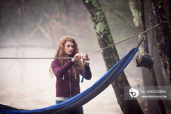 Young female hiker hanging metal cup on rope