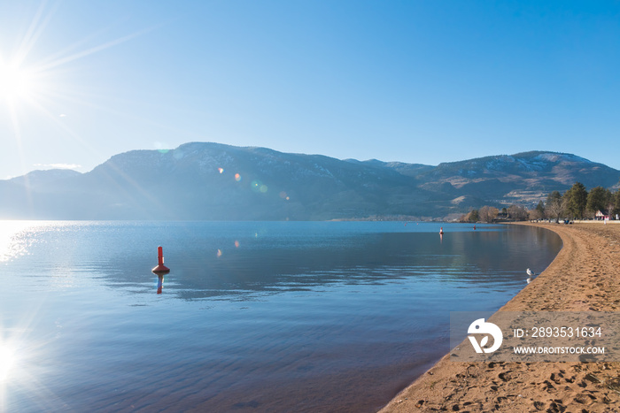 Sun shining on Skaha Beach, lake, and mountains in Penticton, British Columbia, Canada