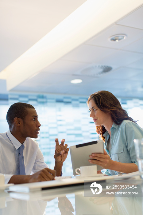 Business people with digital tablet talking in meeting