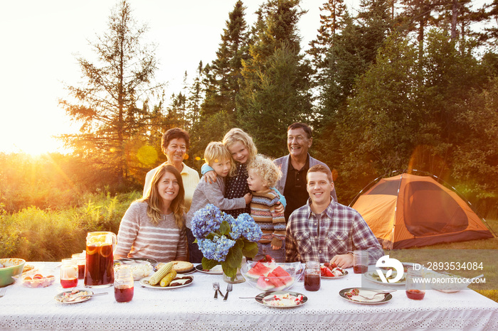 Family with children (2-3, 4-5, 6-7) at dining table outdoors