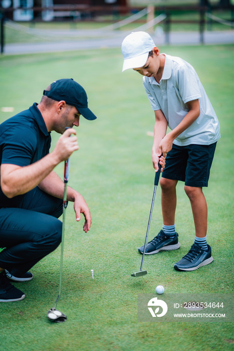 Learning Golf. Boy practicing putting with instructor