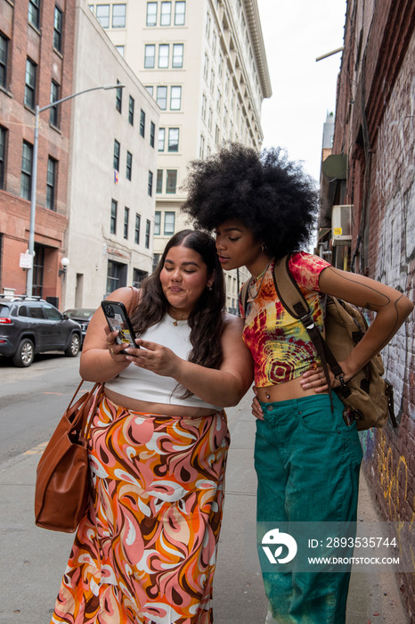 USA, New York City, Two women using phone in street