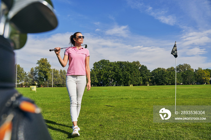 Female golfer walking on the green grass