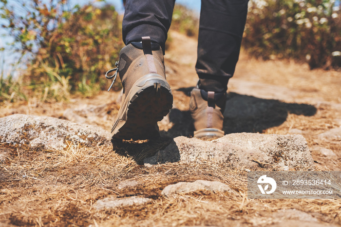 Closeup image of a woman hiking with trekking boots on the top of mountain