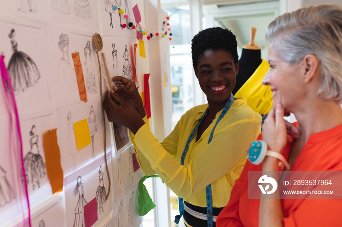 Female fashion designers discussing over sketch design