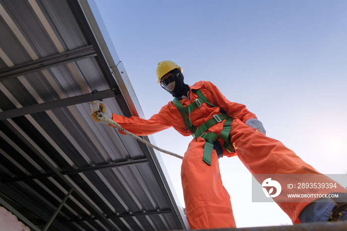 Working at height equipment . Builder Worker in safety protective equipment on roof construction sit