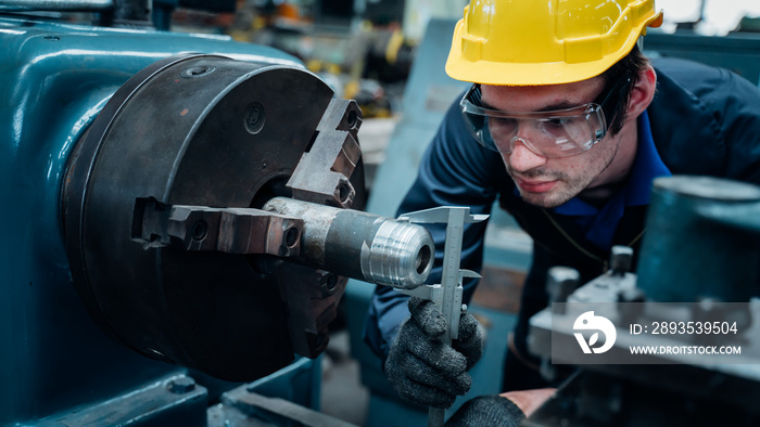 Work at the Heavy Industry Manufacturing Facility concept.Worker measuring on industrial turning mac