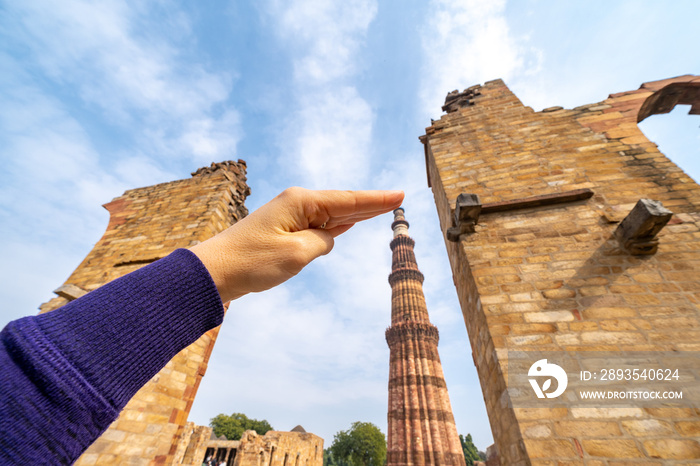 游客在新德里拍摄了一张强迫透视照片，照片中她的手触摸了Qutub Minar柱。