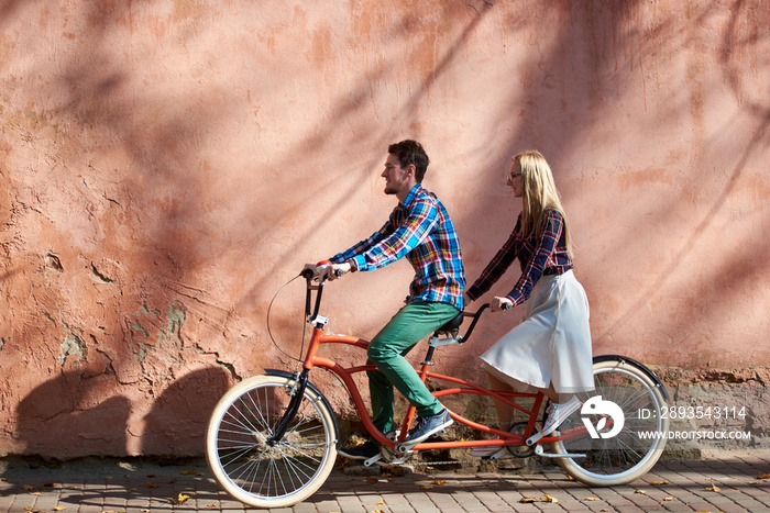 年轻迷人的旅游情侣，穿着休闲服，大胡子男人和金发女人骑双人自行车