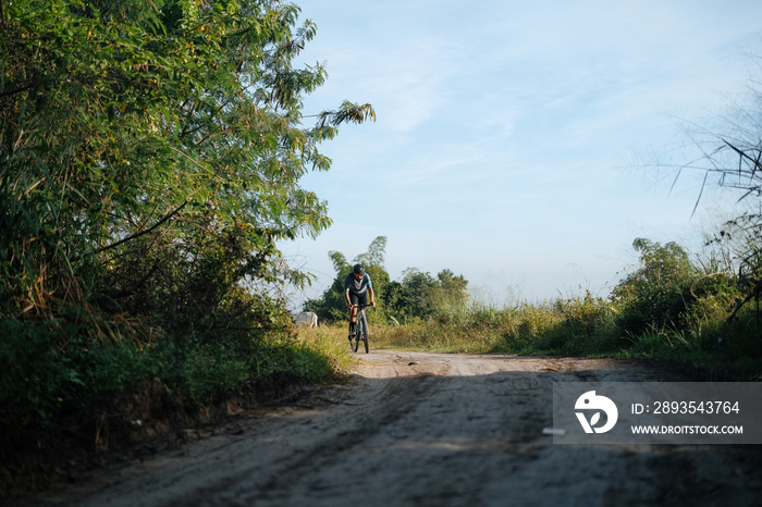 A young bearded cyclist is biking through a dirt path.