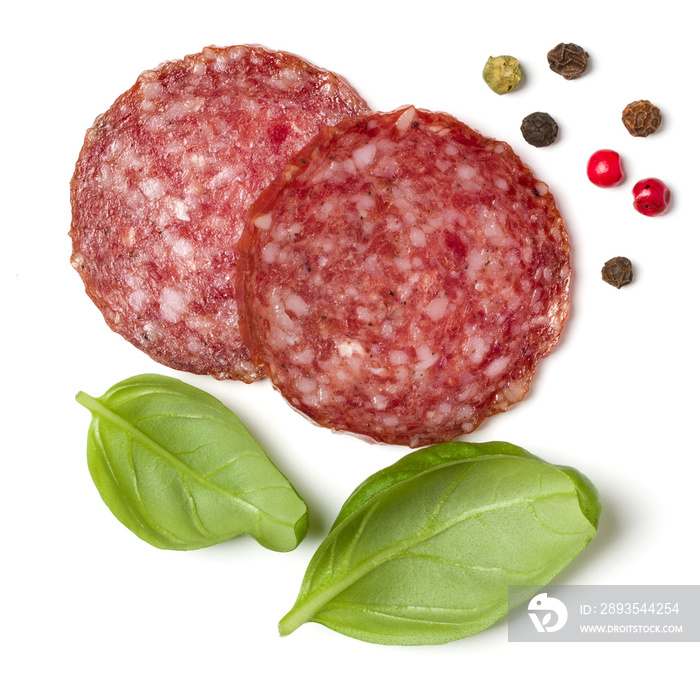 Slices of salami isolated on white background closeup. Sausage and basil leaves top view.