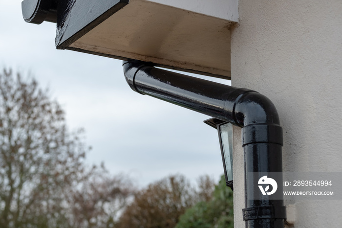 Detailed view of a newly painted gutter and down pipe drainage system seen together with part of a s