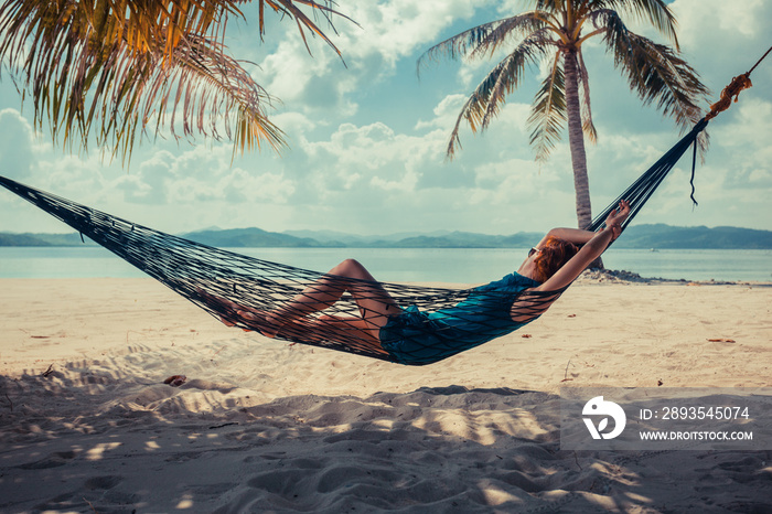在热带海滩吊床上放松的女人