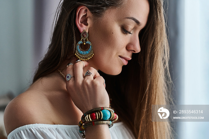 时尚性感的深色波西米亚风格的女人戴着大耳环、带石戒指和银戒指的手镯。F