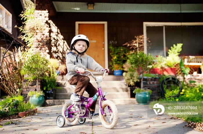 Portrait of boy with bicycle against house