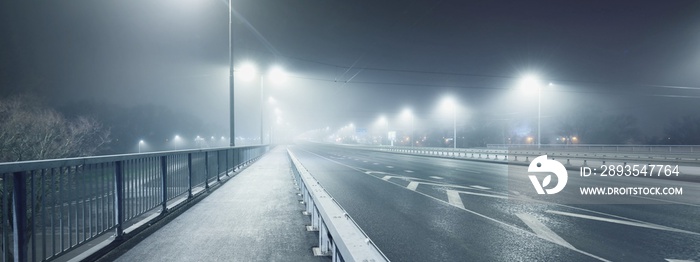 夜间雾中高速公路附近一条空荡荡的有照明的自行车道（人行道）。灯笼