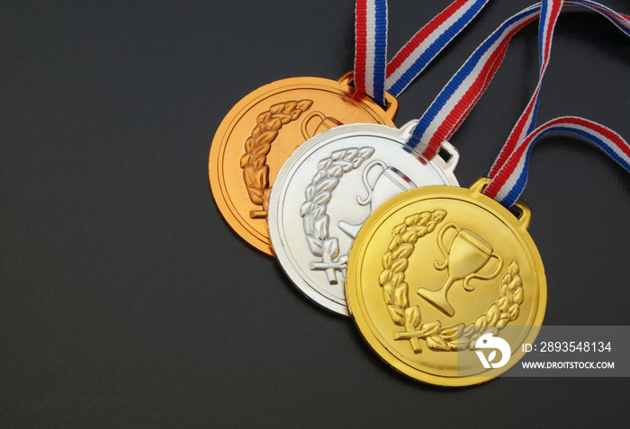 Gold, silver and bronze medal with ribbons on black board