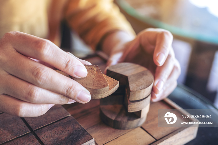 Closeup image of people playing and building round wooden puzzle game