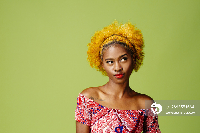 Young woman with curly hair looking up, isolated on green studio background