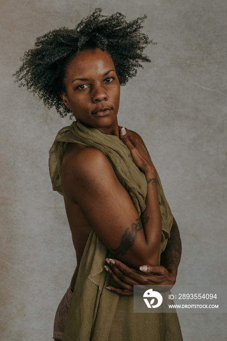 African American woman with an afro hugging herself looking at camera