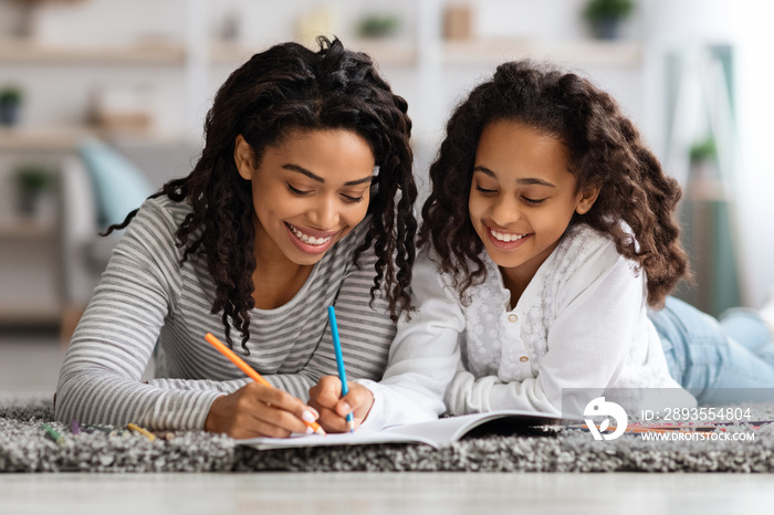 Joyful mother and daughter drawing together at home