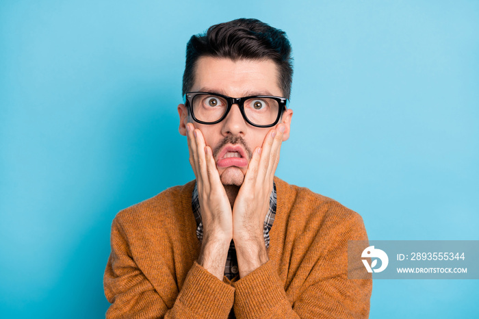 Photo of young man amazed shocked surprised stupor hands touch cheeks isolated over blue color backg