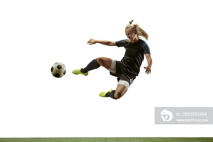 年轻的女足球运动员或足球运动员，留着长发，穿着运动服和靴子踢球