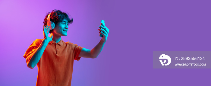 Young man talking on phone isolated over pink purple background in neon light