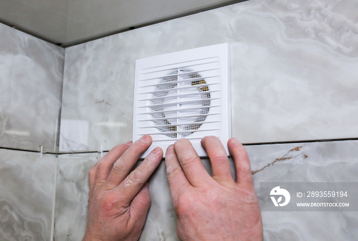 Man is making the wall bathroom fan vent. Restoration process.