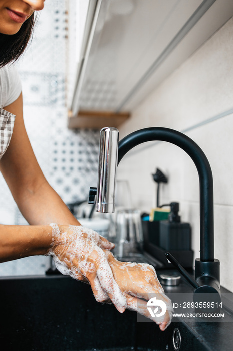 年轻成年女性在厨房水槽上洗手。家庭、家庭和个人卫生常规