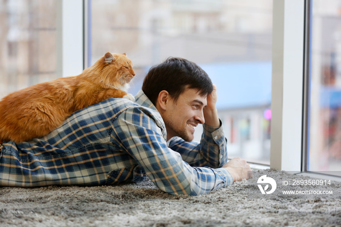 一个年轻人和一只毛茸茸的猫躺在地毯上
