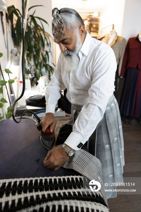 gray hair bearded man wearing skirt and ironing