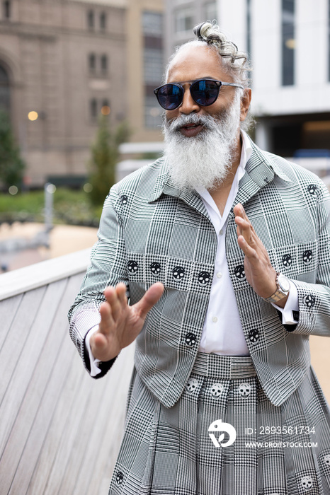 gray hair bearded man wearing skirt suit laughing and gesturing