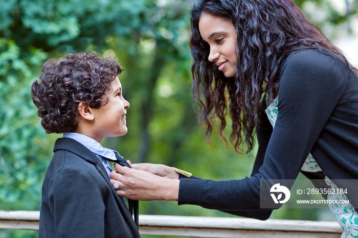 Mother helping with tie to son (6-7)