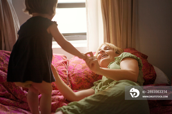 Mother with daughter (2-3) playing in bedroom