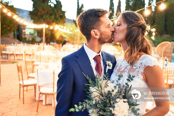 Young beautiful couple smiling happy and confident getting married. Standing with smile on face kiss