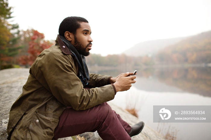 Man looking away while sitting at lakeshore