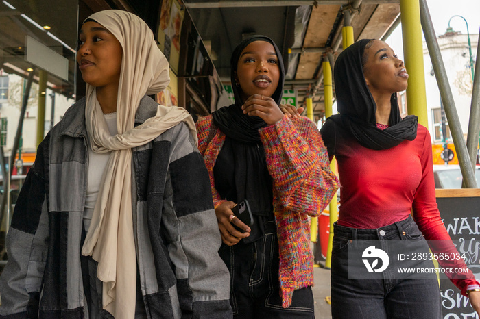 Smiling young women wearing�hijabs�walking in city