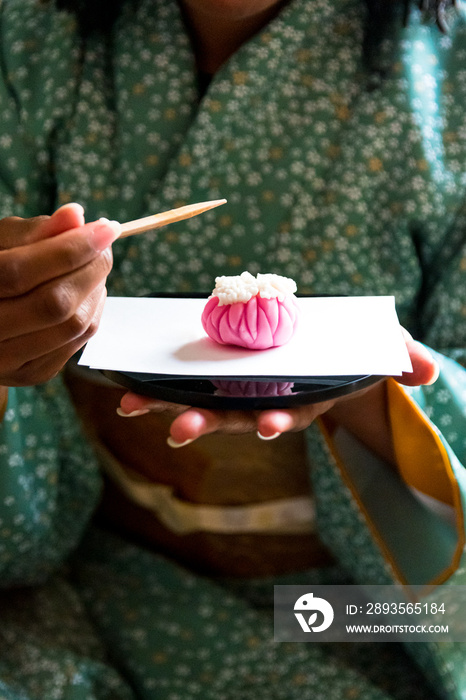 黑人妇女准备在日本传统茶会上吃Wagashi，日本传统糖果