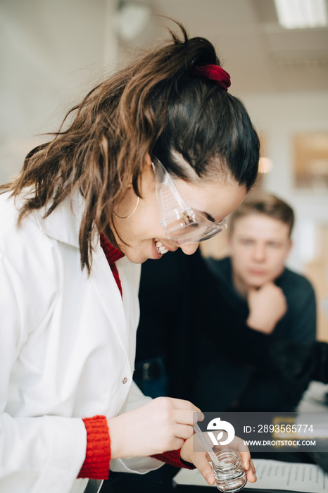 Smiling teenage student doing scientific experiment in chemistry class