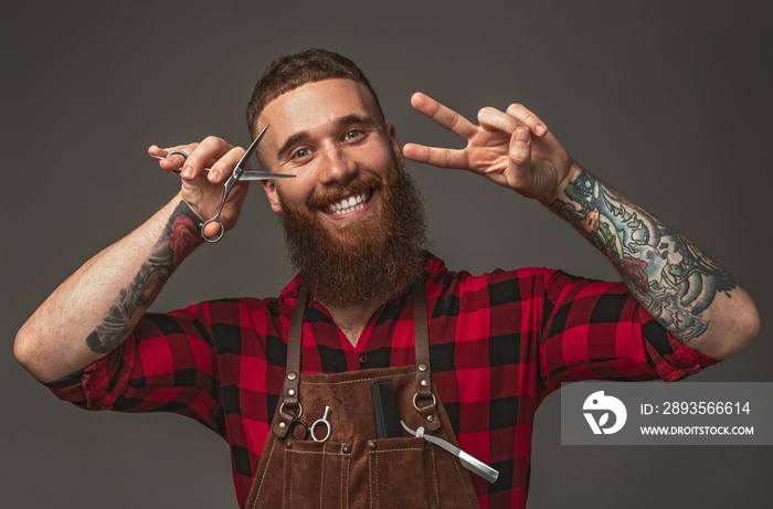 Cheerful barber with scissors gesturing V sign