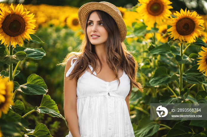 Young woman in white dress and straw hat on the field on a sunny day.