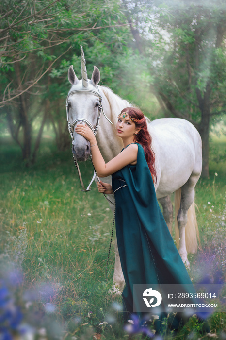 An elf with a unicorn. Beautiful girl in a green dress in nature with a white horse. Model in a medi