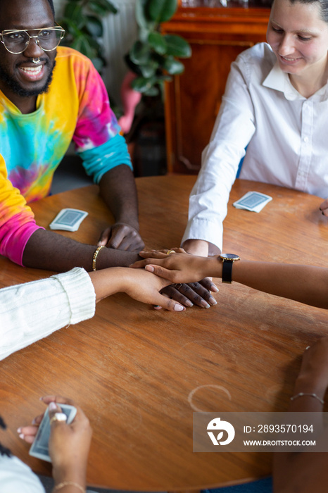 Group of friends holding hands together at table�