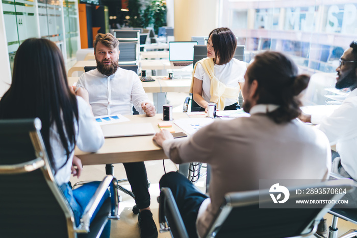 Confident man explaining business strategy to group of multiethnic colleagues