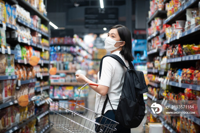 亚洲女性戴防护口罩预防病毒和污染，在超市购物购买食品