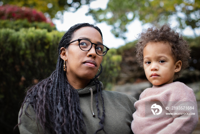 Black mother holding toddler boy and smiling in fall