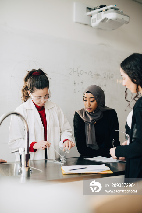 Female students doing scientific experiment at high school laboratory