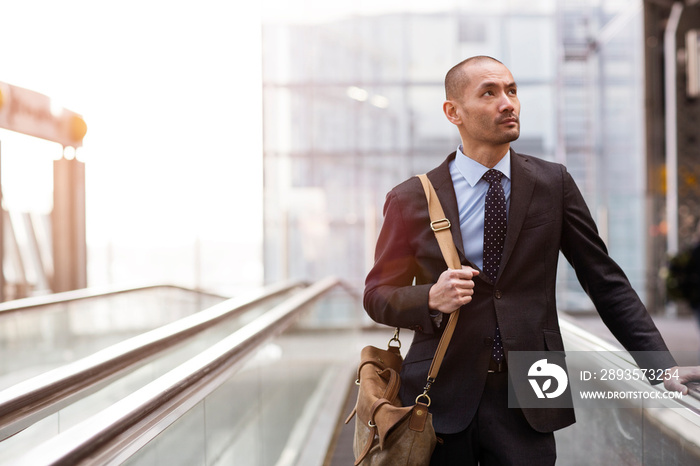 Businessman moving down on escalator