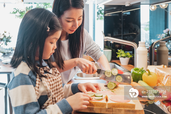 Asian Mother and her daughter kid cooking food for breakfast in kitchen